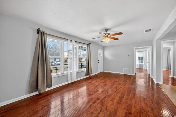 a view of empty room with wooden floor and fan