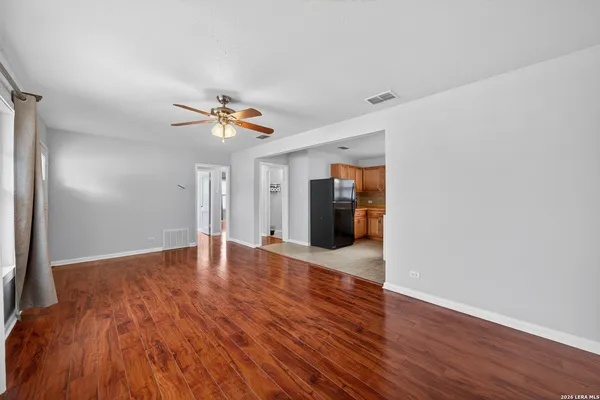 a view of an empty room with wooden floor and a ceiling fan