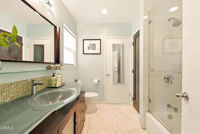 a bathroom with a granite countertop sink a mirror a bathtub and shower