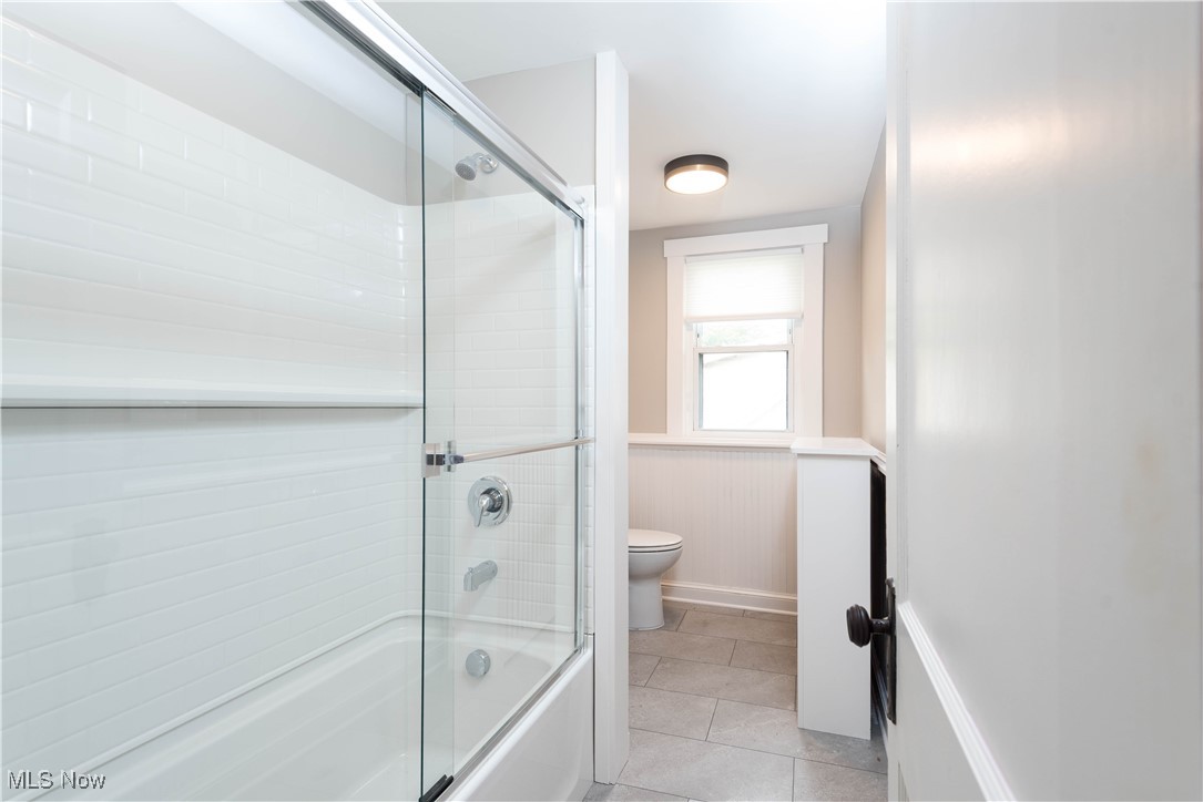 7003 Brecksville Road Independence, OH 44131 - Photo 23 of 35 Full bathroom with combined bath / shower with glass door, light tile patterned floors, and a wainscoted wall