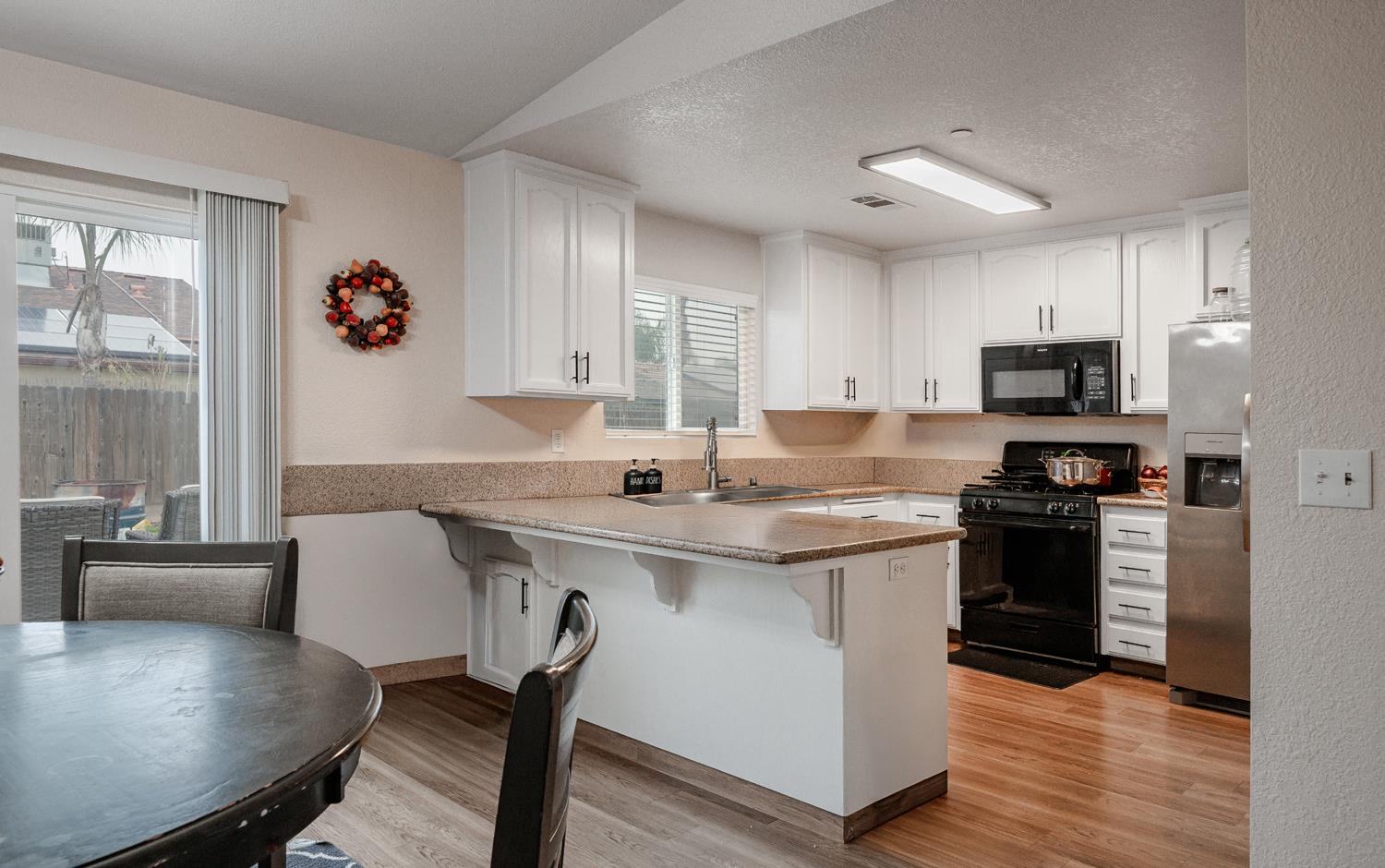 1935 Madison Drive Madera, CA 93638 - Photo 9 of 22 a kitchen with stainless steel appliances granite countertop a stove top oven a sink dishwasher a dining table and chairs with wooden floor