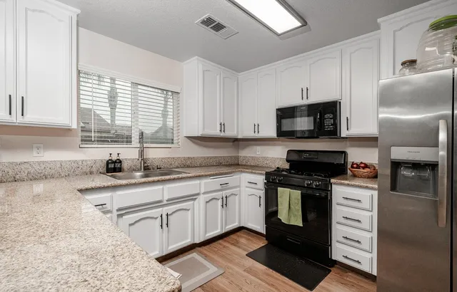 a kitchen with stainless steel appliances granite countertop a sink a stove a refrigerator cabinets and a window