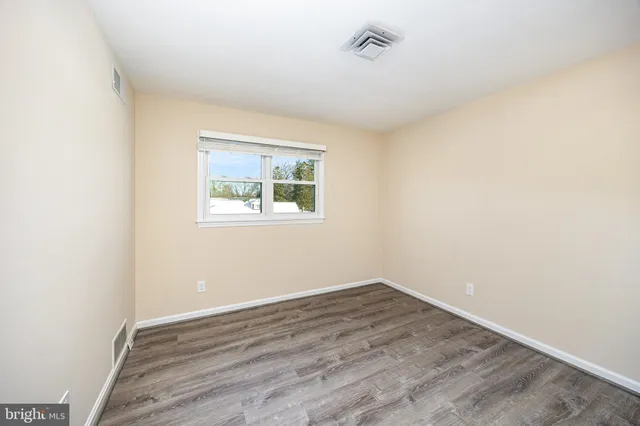 an empty room with wooden floor and window