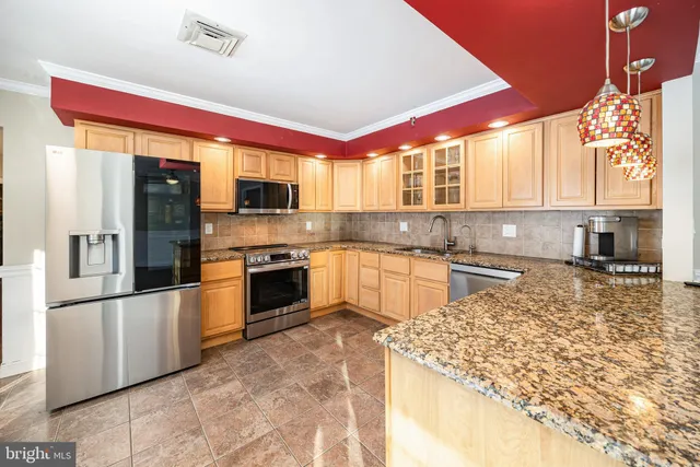 a large kitchen with stainless steel appliances granite countertop a stove a sink and a refrigerator