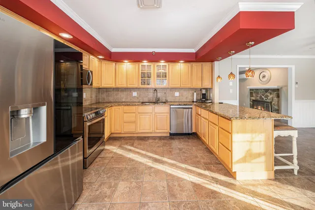 a view of a hallway with granite countertop a couch and white cabinets next to a window