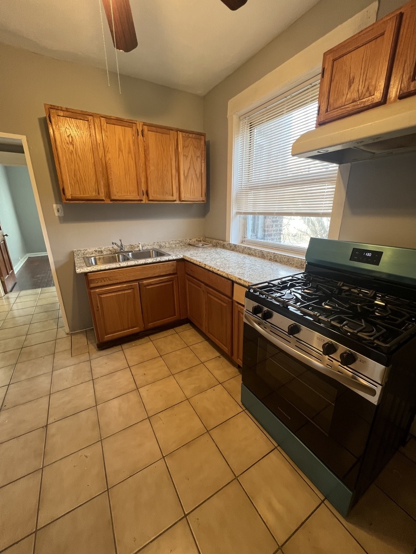 840 West 66th Street, Unit 2 Chicago, IL 60621 - Photo 7 of 7 a kitchen with granite countertop a stove a sink and a microwave