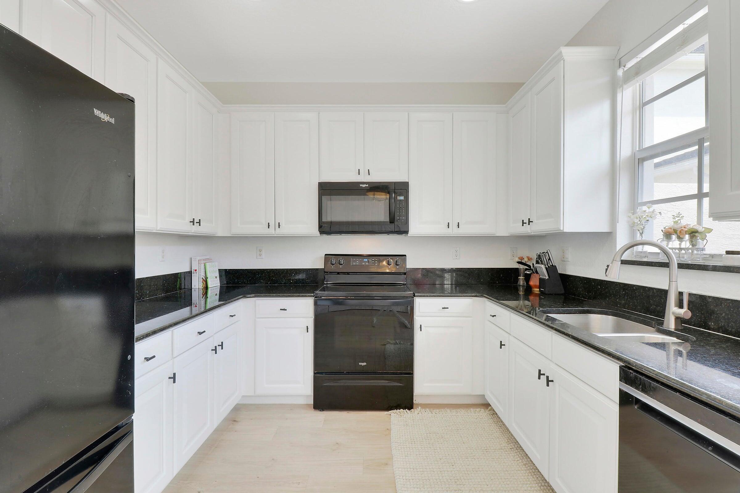 151 Mulligan Place Jupiter, FL 33458 - Photo 11 of 23 a kitchen with granite countertop white cabinets and white appliances