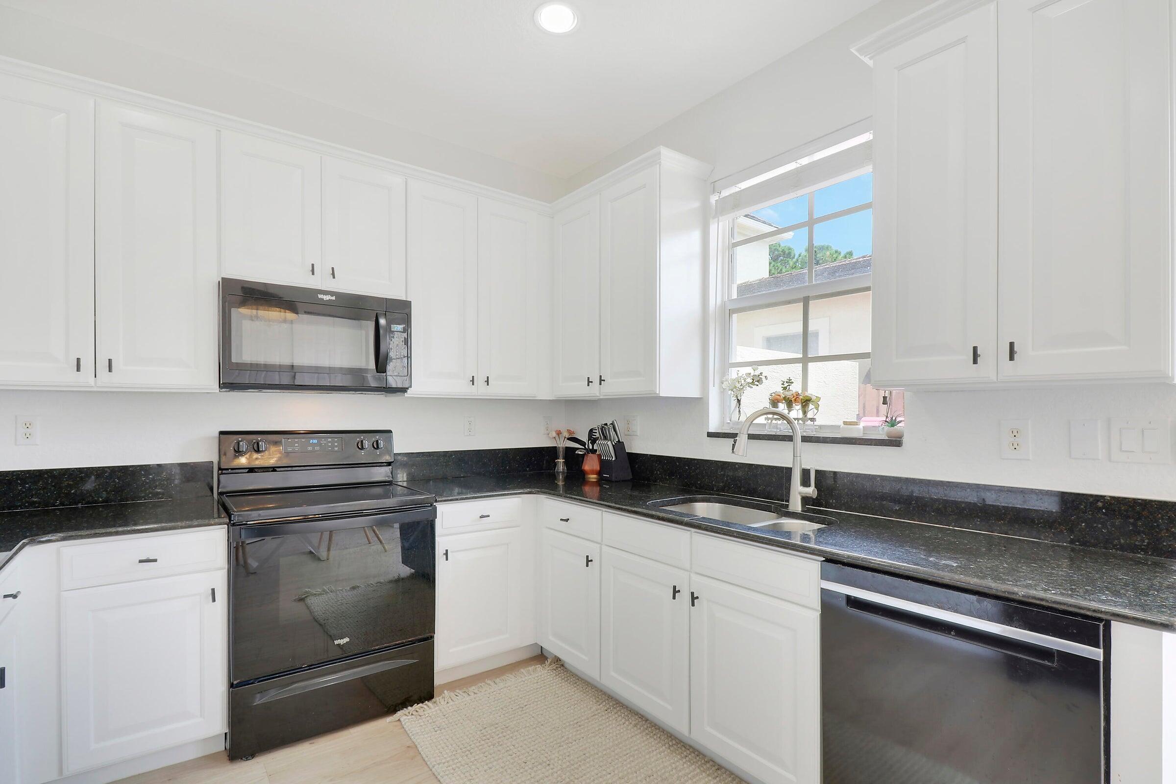 151 Mulligan Place Jupiter, FL 33458 - Photo 10 of 23 a kitchen with granite countertop white cabinets white appliances and a sink