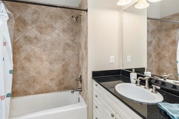 a bathroom with a granite countertop sink a mirror and a bathtub
