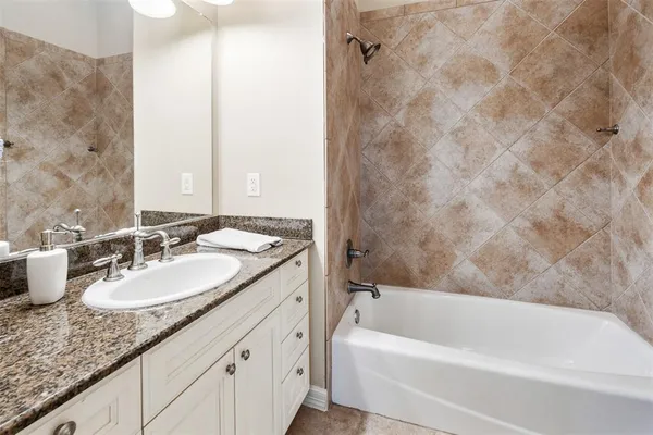a bathroom with a granite countertop sink and a bathtub