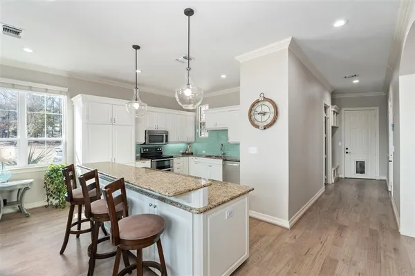 a kitchen with a table chairs a sink dishwasher and a stove with wooden floor