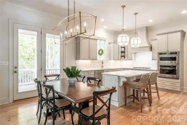 a kitchen with stainless steel appliances a dining table chairs and wooden floor