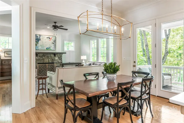 a dining room with wooden floor a chandelier a glass table and chairs