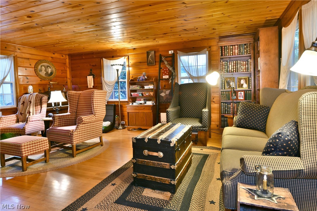 8683 King Graves Road Northeast Warren, OH 44484 - Photo 19 of 50 Wood-paneled living space featuring a wood-finish ceiling, hardwood flooring, and exposed log walls