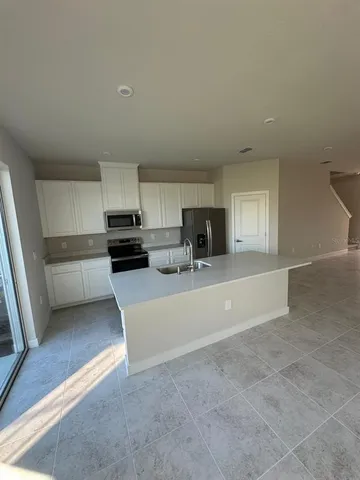 a view of kitchen with stainless steel appliances granite countertop a refrigerator a sink a stove a microwave and cabinets