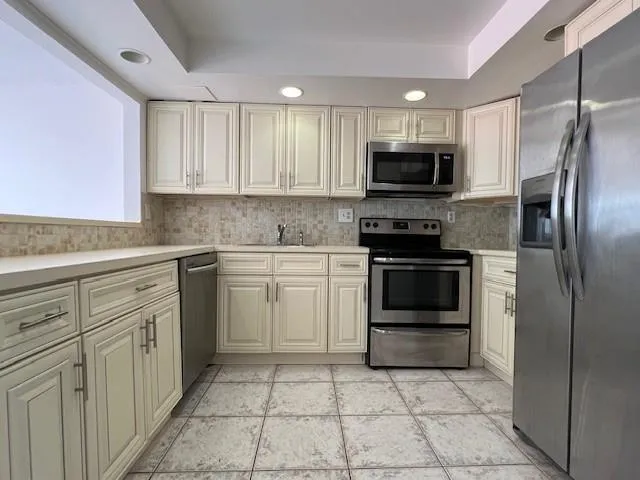 a kitchen with cabinets stainless steel appliances and a window