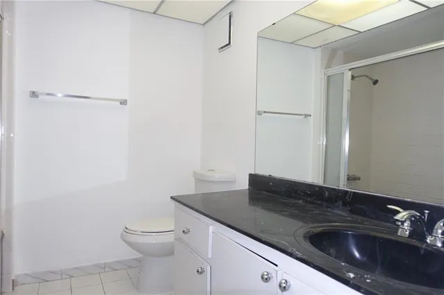 a bathroom with a granite countertop sink and a toilet
