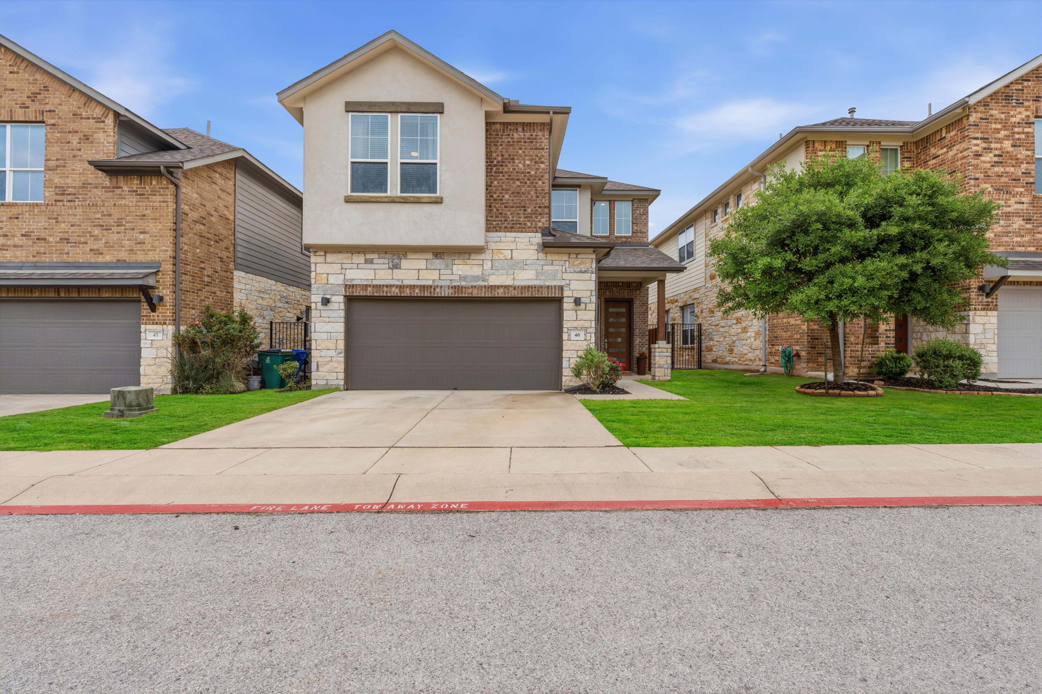 900 Old Mill Road, Unit 46 Cedar Park, TX 78613 - Photo 29 of 30 View of front of property with a front lawn, a garage, stone siding, driveway, and stucco siding
