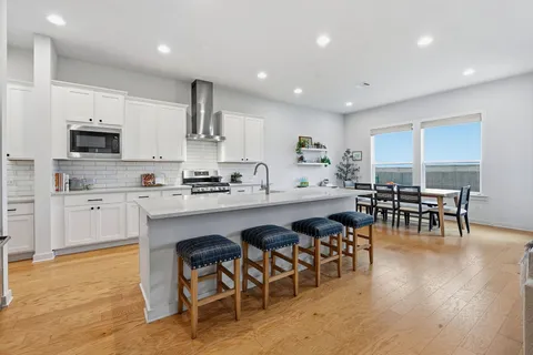 a kitchen with stainless steel appliances granite countertop a table chairs microwave and sink