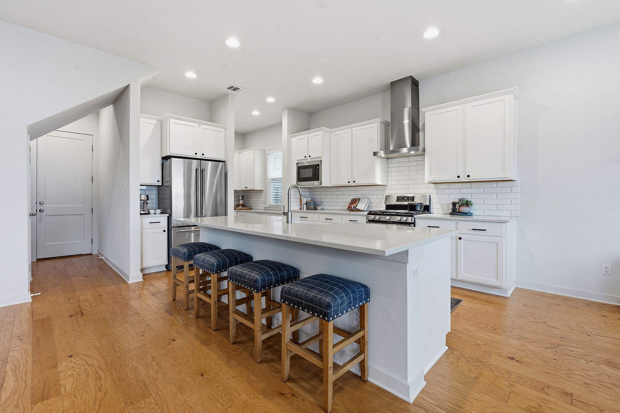 900 Old Mill Road, Unit 46 Cedar Park, TX 78613 - Photo 10 of 30 Kitchen with a center island with sink, white cabinetry, a kitchen bar, stainless steel appliances, and light wood finished floors