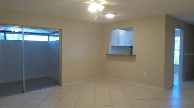 a view of an empty room with wooden floor and fan