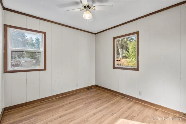 a view of empty room with wooden floor and fan