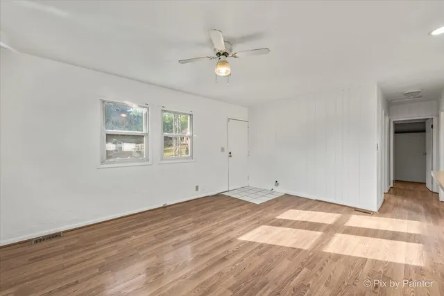 a view of a room with wooden floor and a ceiling fan