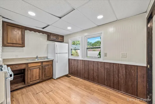 a kitchen with stainless steel appliances granite countertop a refrigerator a sink dishwasher a stove and white countertops with wooden floor