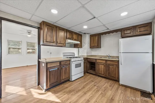 a kitchen with stainless steel appliances granite countertop a stove top oven a sink and a refrigerator
