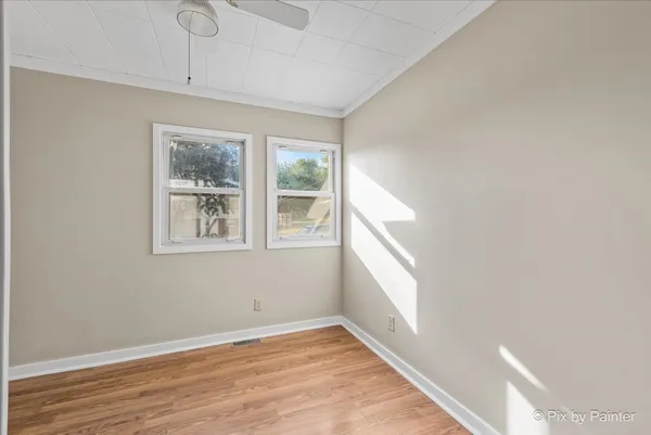 a view of an empty room with a window and wooden floor