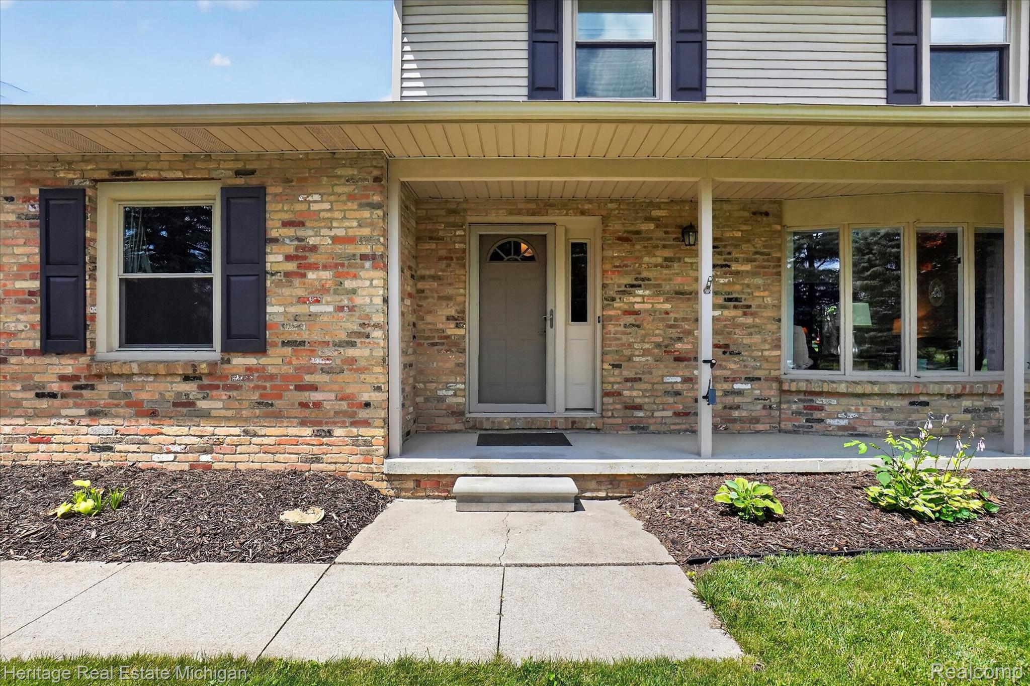 14038 North Hogan Road Linden, MI 48451 - Photo 50 of 53 Brick facade with vertical siding accents, featuring a covered porch, bay window, and a concrete pathway