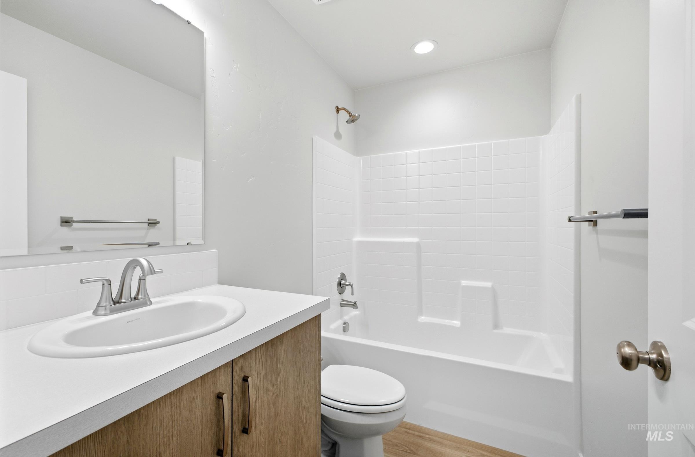 16434 Backfill Avenue Caldwell, ID 83607 - Photo 14 of 19 Wood-finish vanity with an integrated sink, brushed nickel faucet, and a wall-mounted mirror