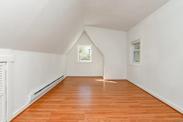 a view of an empty room with window and wooden floor