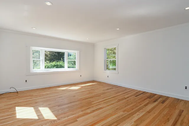 an empty room with wooden floor and windows