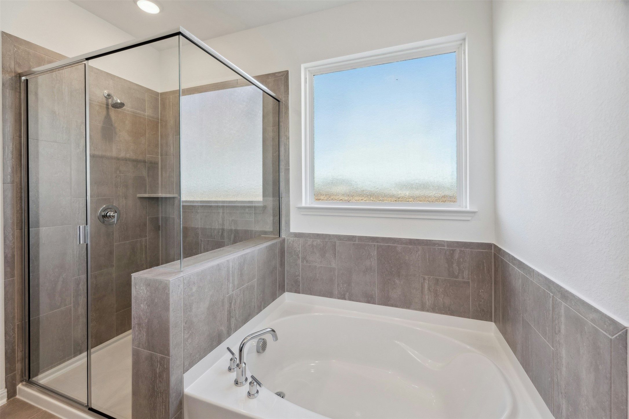 2001 Wynn Road Hutto, TX 78634 - Photo 16 of 39 A well-appointed primary bathroom showcases a deep soaking tub and a spacious, glass-enclosed shower.
