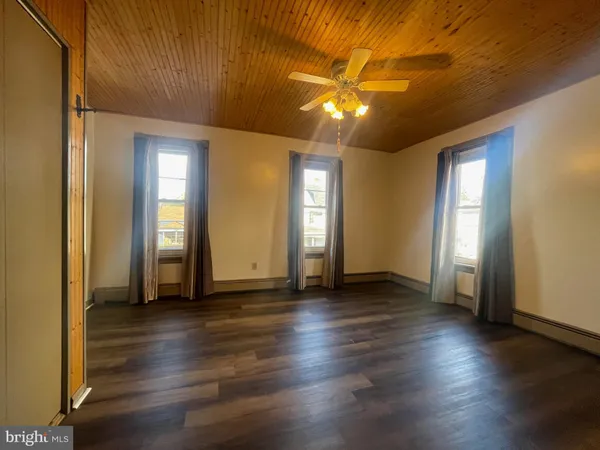 an empty room with wooden floor fan and window