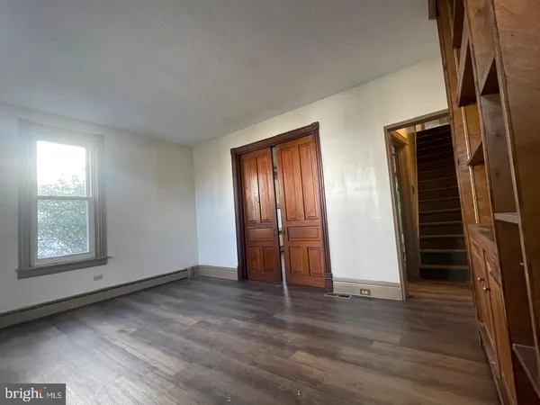 an empty room with wooden floor closet and windows