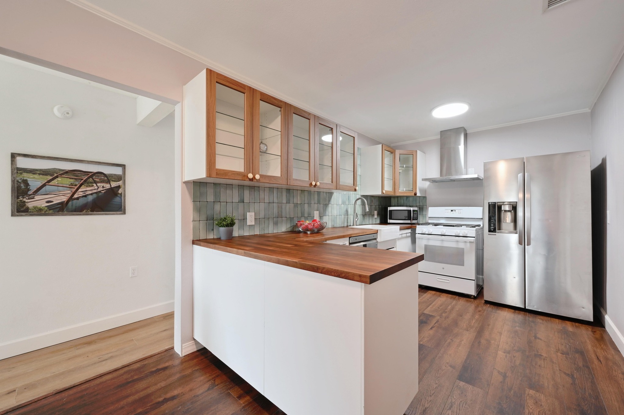 6302 Thurgood Avenue Austin, TX 78721 - Photo 11 of 31 a kitchen with stainless steel appliances granite countertop a refrigerator a sink dishwasher a stove and white countertops with wooden floor
