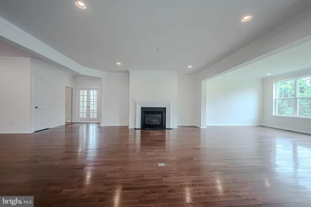 a view of an empty room with window and wooden floor