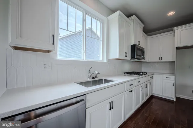 a kitchen with stainless steel appliances white cabinets and a sink