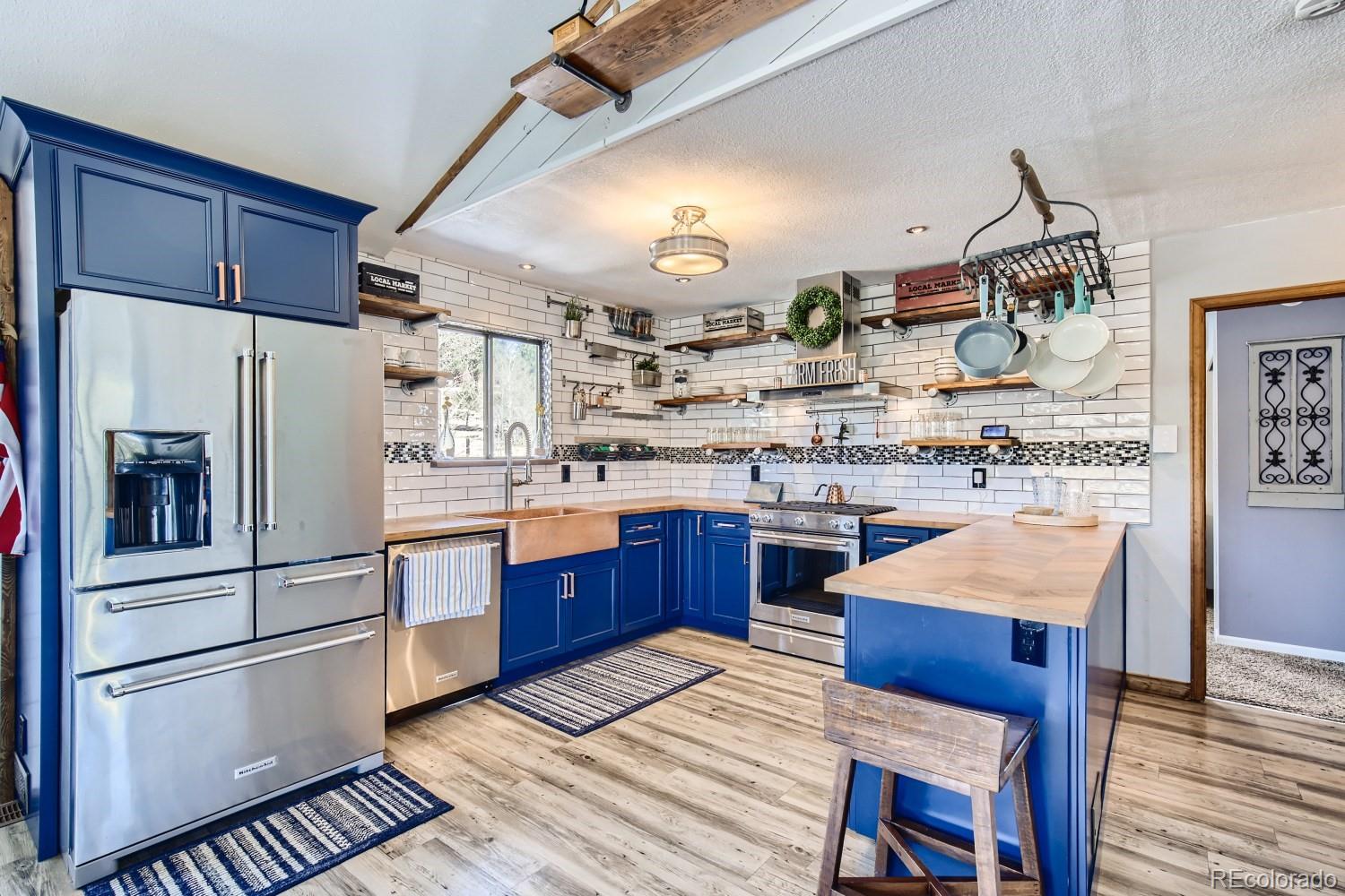 44 Bandit Lane Bailey, CO 80421 - Photo 2 of 30 a kitchen with stainless steel appliances granite countertop a refrigerator a sink dishwasher a stove and white countertops with wooden floor