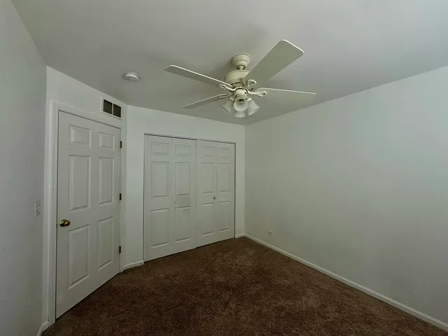 an empty room with a fan & a ceiling fan