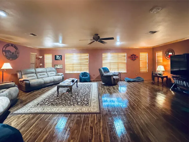 a living room with furniture dining table wooden floor and a view of kitchen