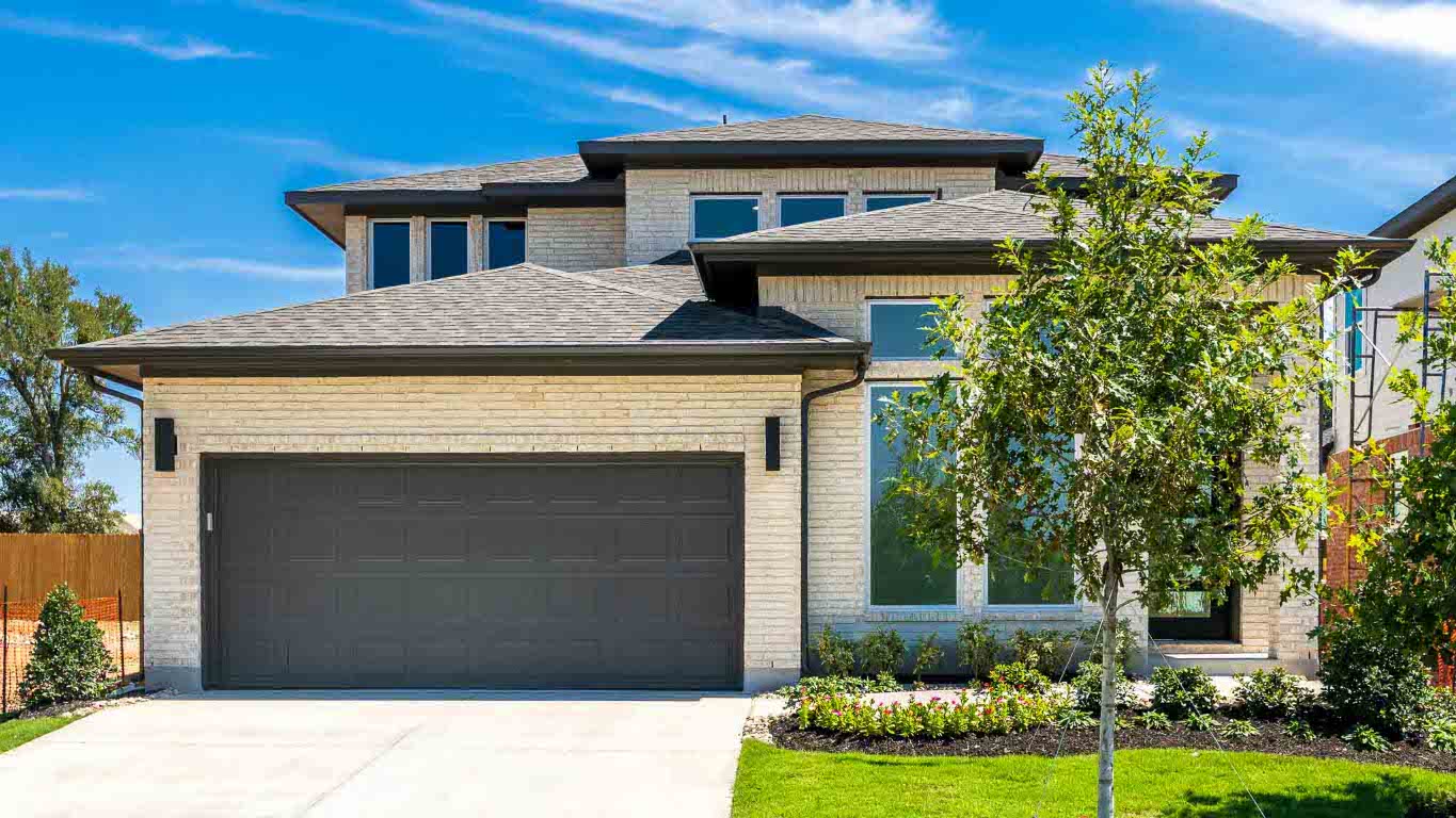 View of front of home featuring a shingled roof, a garage, concrete driveway, and brick siding
