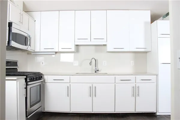 a kitchen with stainless steel appliances granite countertop white cabinets and a sink