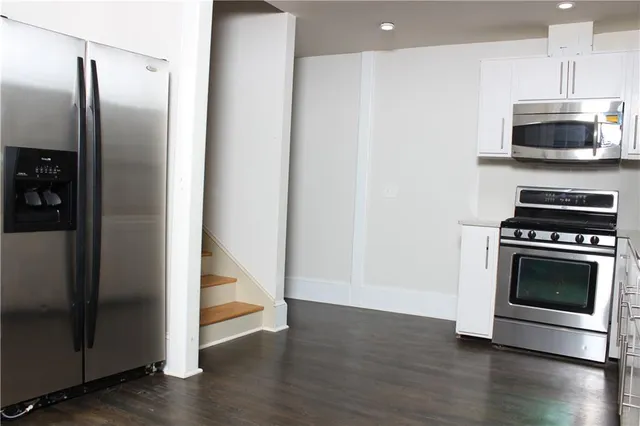 a kitchen with granite countertop a refrigerator and a stove top oven