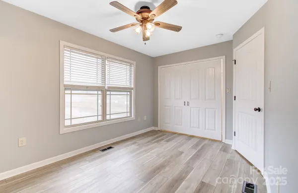 a view of an empty room with window and a chandelier fan