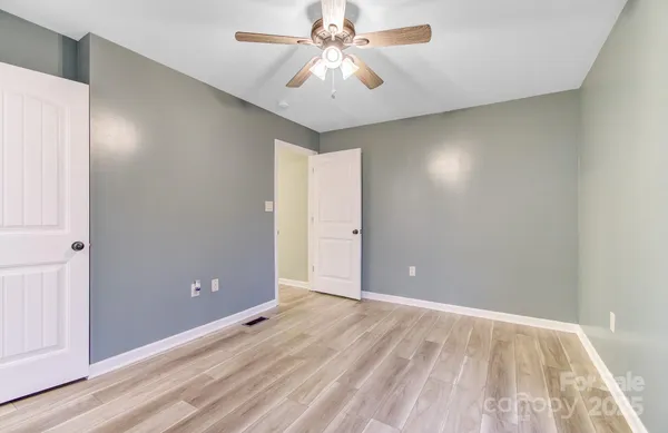 a view of an empty room and chandelier fan