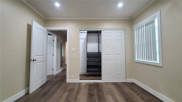 an empty room with wooden floor closet and windows