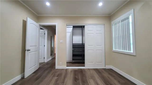 an empty room with wooden floor closet and windows